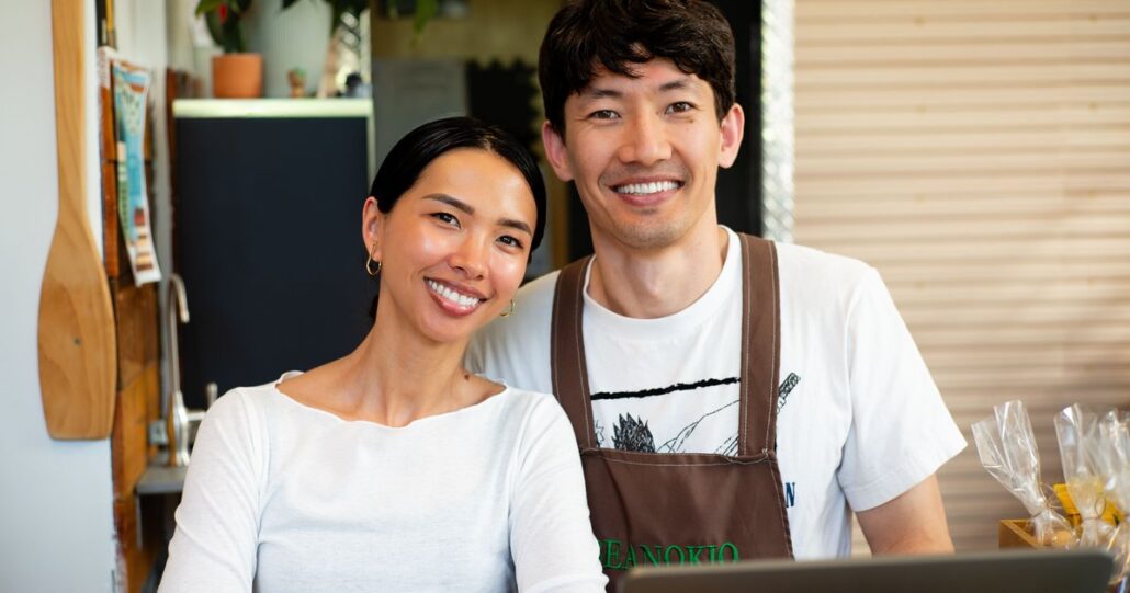 Two smiling shop owners behind their counter